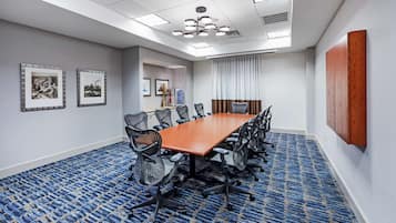 A conference room with a long table, chairs, and a blue patterned carpet.