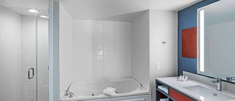 A modern bathroom with a glass-enclosed shower, a freestanding bathtub, and a vanity with a large mirror.