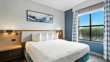 Una habitación de hotel moderna con una cama grande, cabecera con iluminación integrada, un cuadro abstracto colgado en la pared y un amplio ventanal con cortinas.
