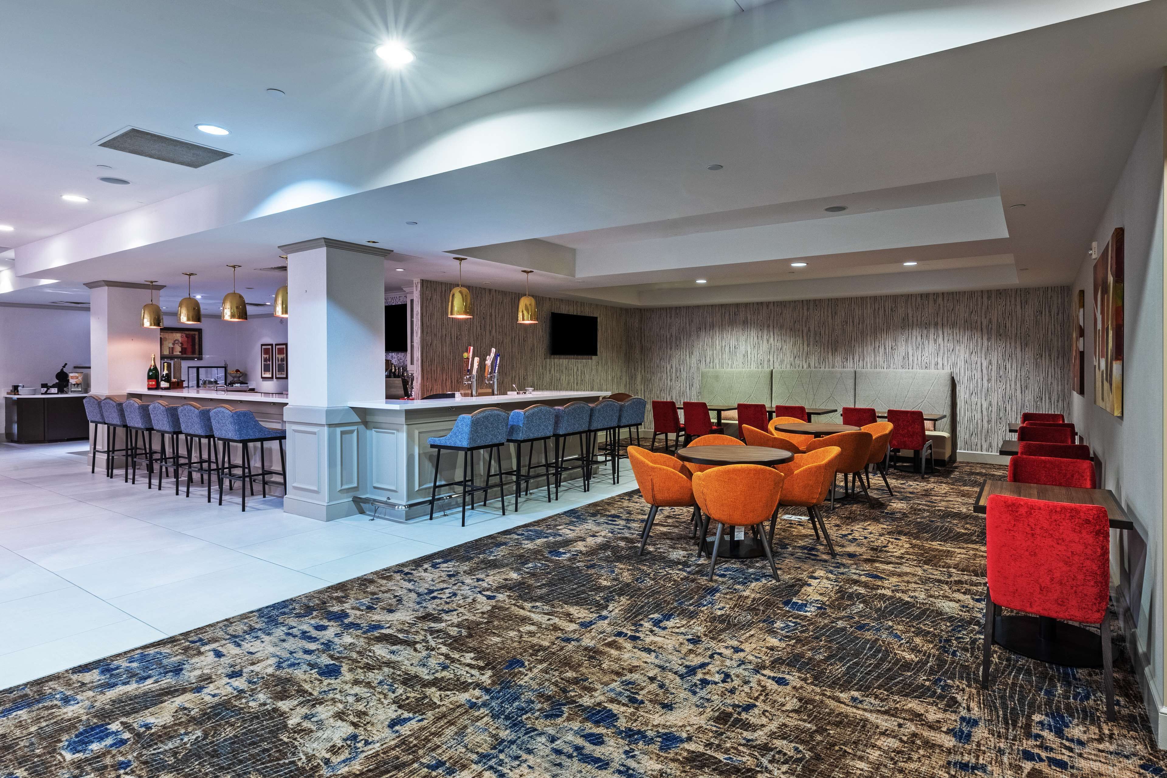 A spacious lobby with a bar area, seating arrangements, and a patterned carpet.