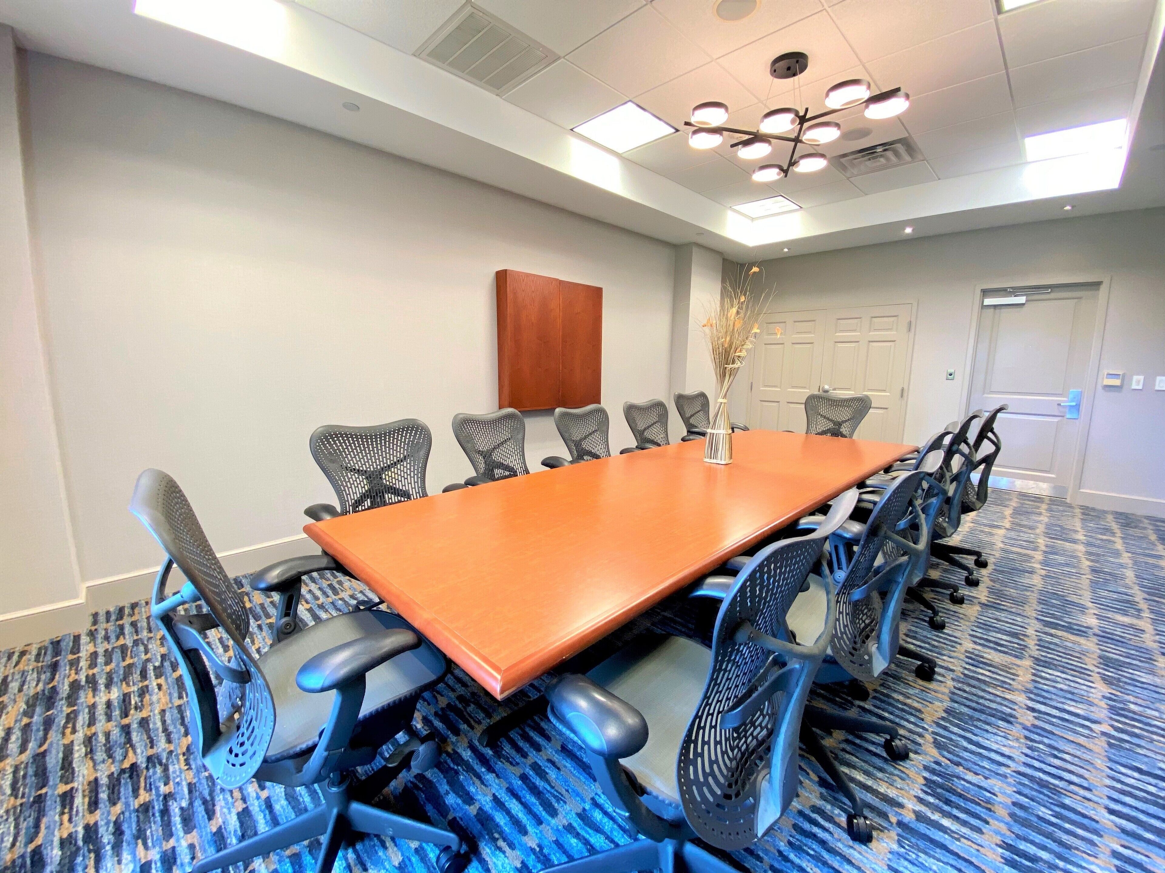 A conference room with a long table, multiple chairs, and a decorative vase.