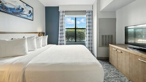 A hotel room with a large bed, a television, a window with curtains, and a painting on the wall. - Hilton Garden Inn Houston/Sugar Land (Sugar Land)