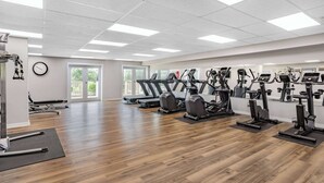 A spacious gym with multiple cardio machines, a treadmill, and a rowing machine.