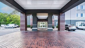A covered entrance with a brick floor, large pillars, and a glass door leading to a building.