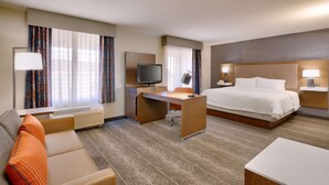 A hotel room with a bed, desk, TV, and a sofa.