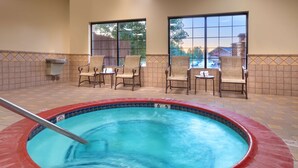 A hot tub with a metal pole, surrounded by four wicker chairs and a small table with a towel.