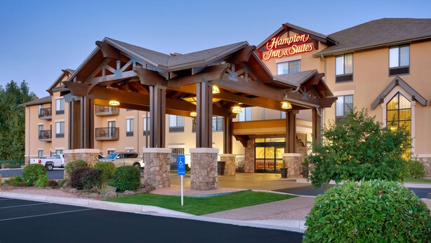 A Hampton Inn & Suites with a covered entrance, stone pillars, and a parking lot.