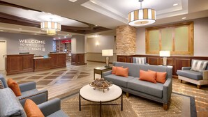 A hotel lobby with a reception desk, seating area, and a large wall with a welcome sign.