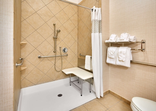 Une salle de bain équipée d’une douche, de toilettes, d’un banc et de porte-serviettes.