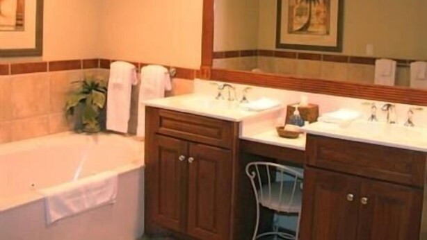 Un baño con dos lavamanos, una bañera y un espejo grande.