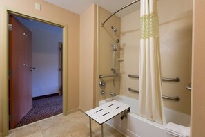 Un baño con ducha, bañera y una pequeña mesa.