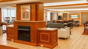 A hotel lobby with a fireplace, seating area, and a dining area. - Hampton Inn Goshen (Goshen)