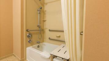 A bathroom with a bathtub, shower, and grab bars.