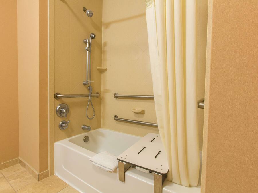 A bathroom with a bathtub, shower, and grab bars.