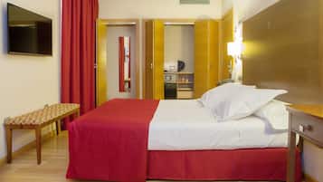 Habitación de hotel con cama, mesita de noche, espejo, armario y televisor.