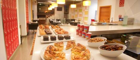 A buffet with various pastries and desserts, including pies and brownies, arranged on a counter.