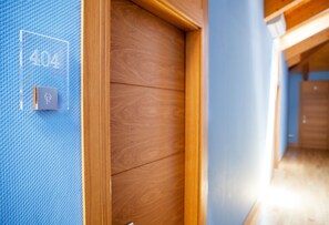 A hotel corridor with a wooden door and a blue textured wall.