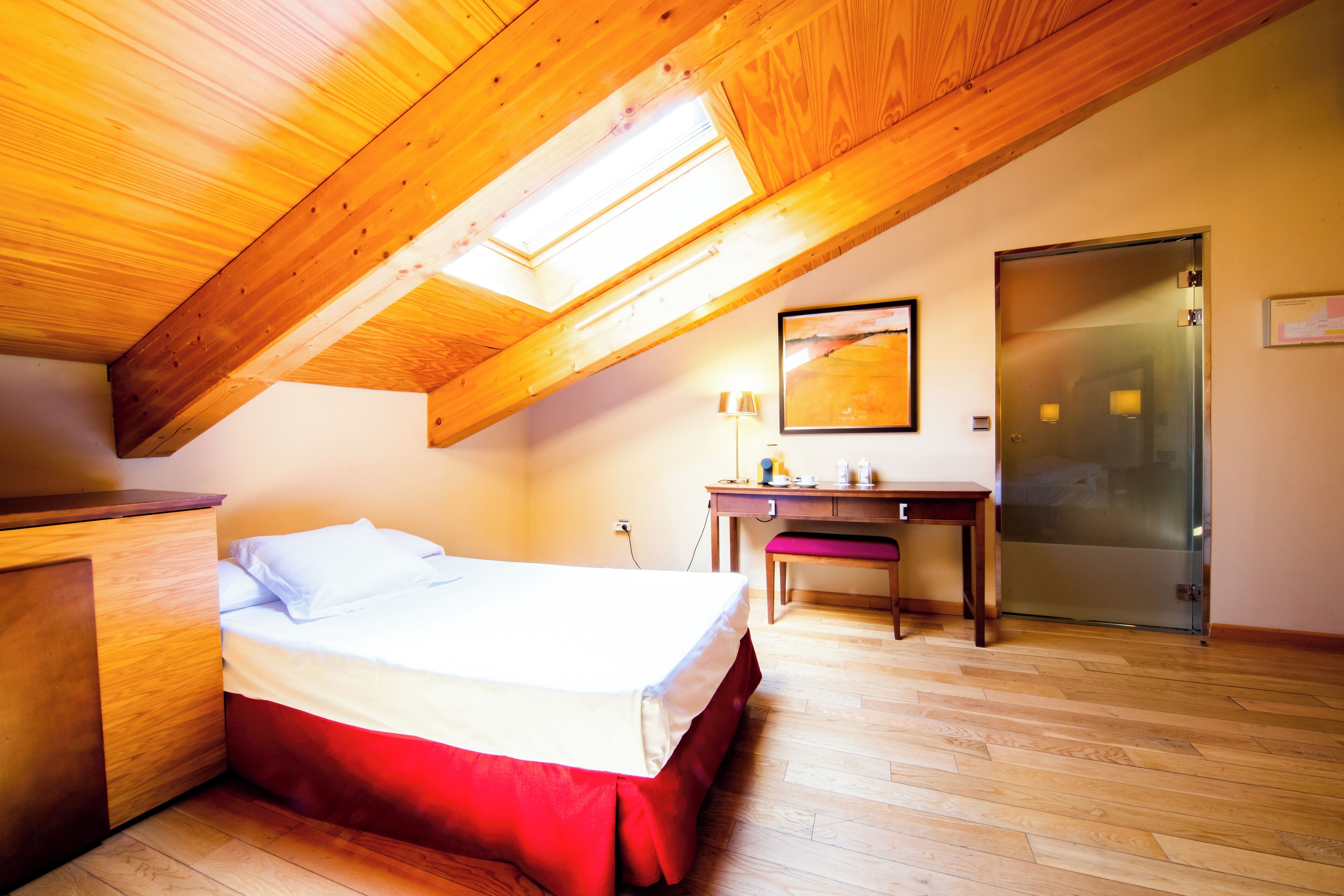 Una habitación con cama, escritorio, silla y puerta corrediza de vidrio.