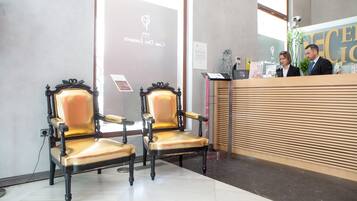 Un área de recepción con dos sillones decorativos, un mostrador de recepción y un ventanal grande.