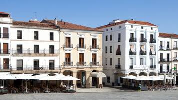 Un espacio cuadrado con mesas al aire libre, edificios blancos y un letrero de restaurante.