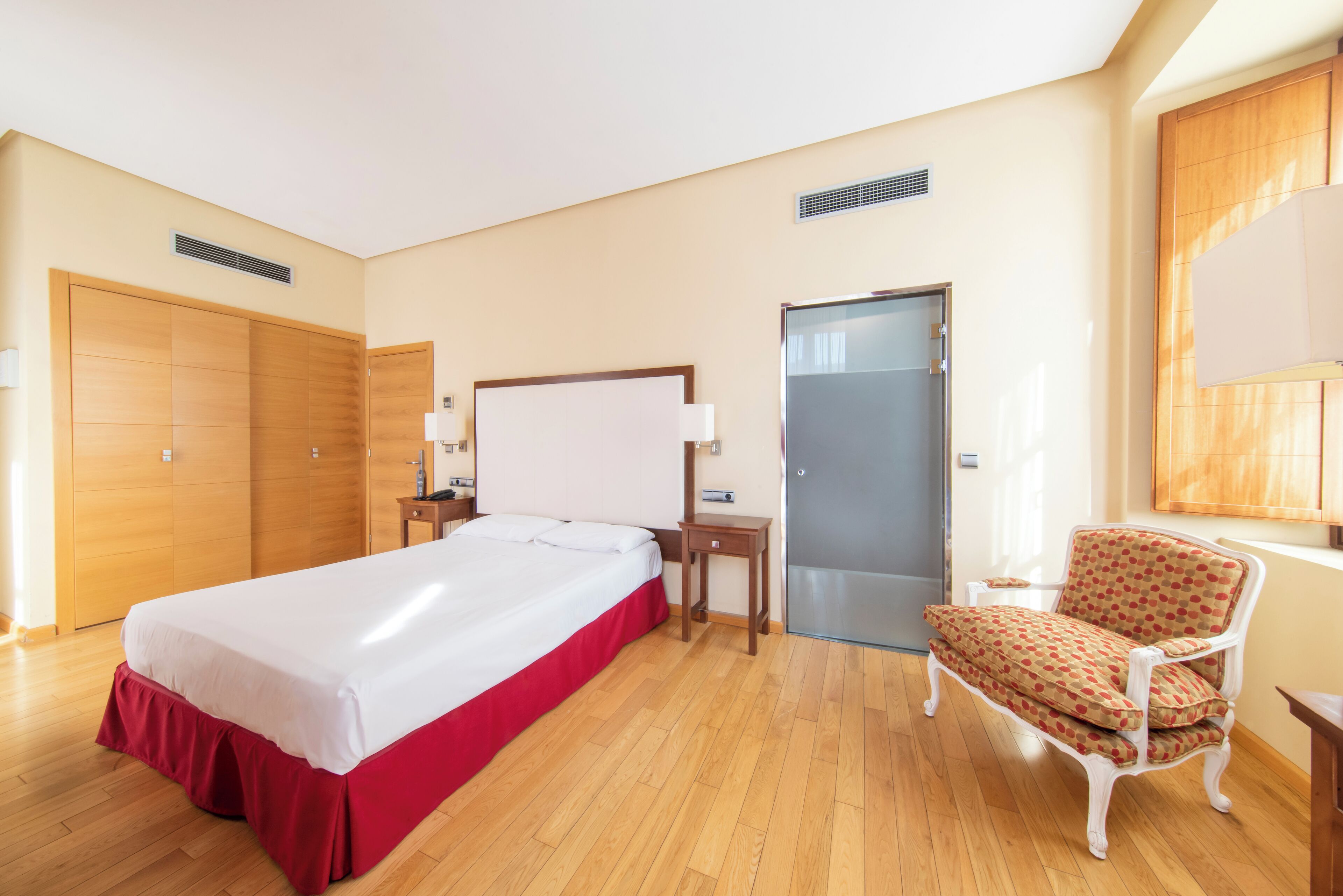Habitación de hotel con cama, una silla, escritorio y armario.