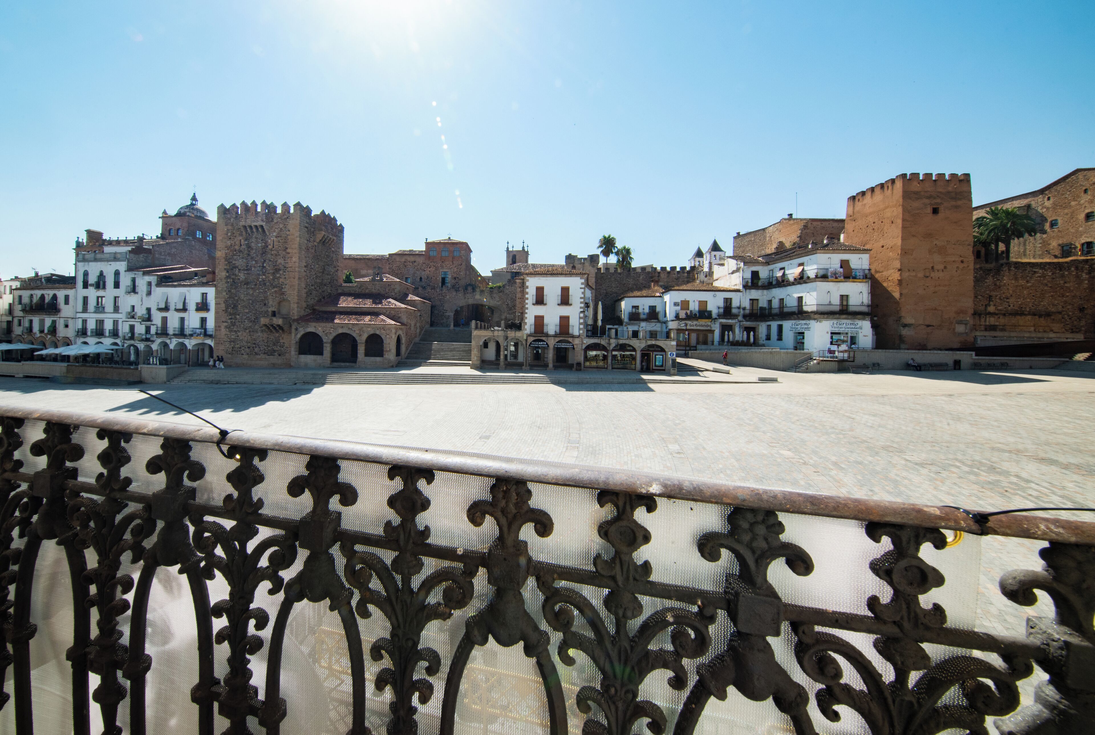 Una plaza histórica con un castillo destacado, edificios tradicionales y un cielo despejado.