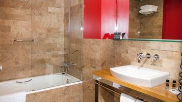 Un baño moderno con ducha de mampara de vidrio, una bañera blanca y un mueble de tocador de madera con lavabo.