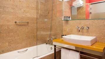 A modern bathroom with a glass-enclosed shower, a white bathtub, and a wooden vanity with a sink.