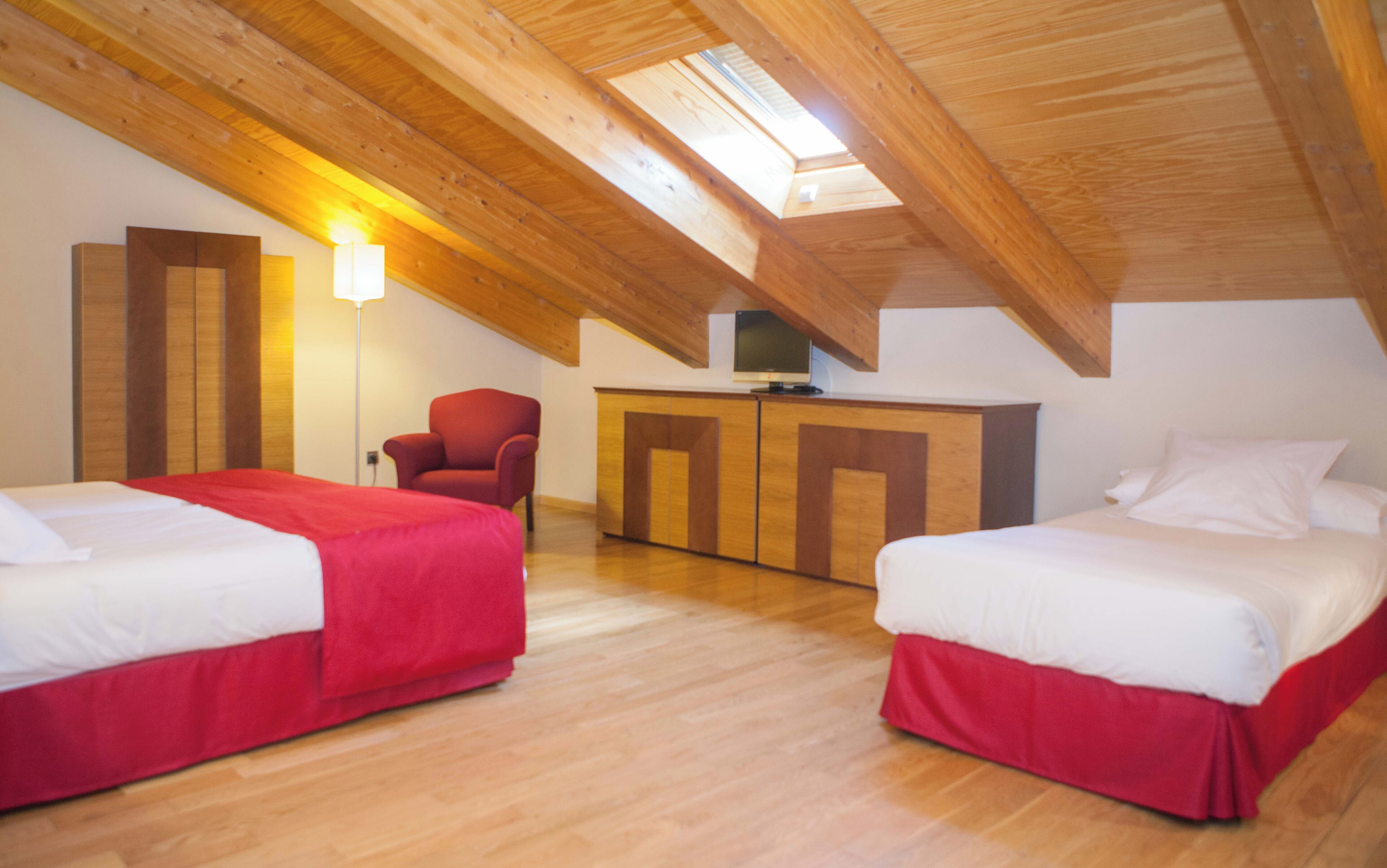 Una habitación con dos camas, una silla, un escritorio y un televisor.