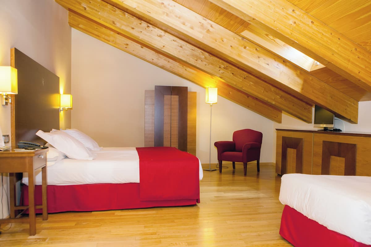 A room with two beds, a desk, a chair, and a TV.