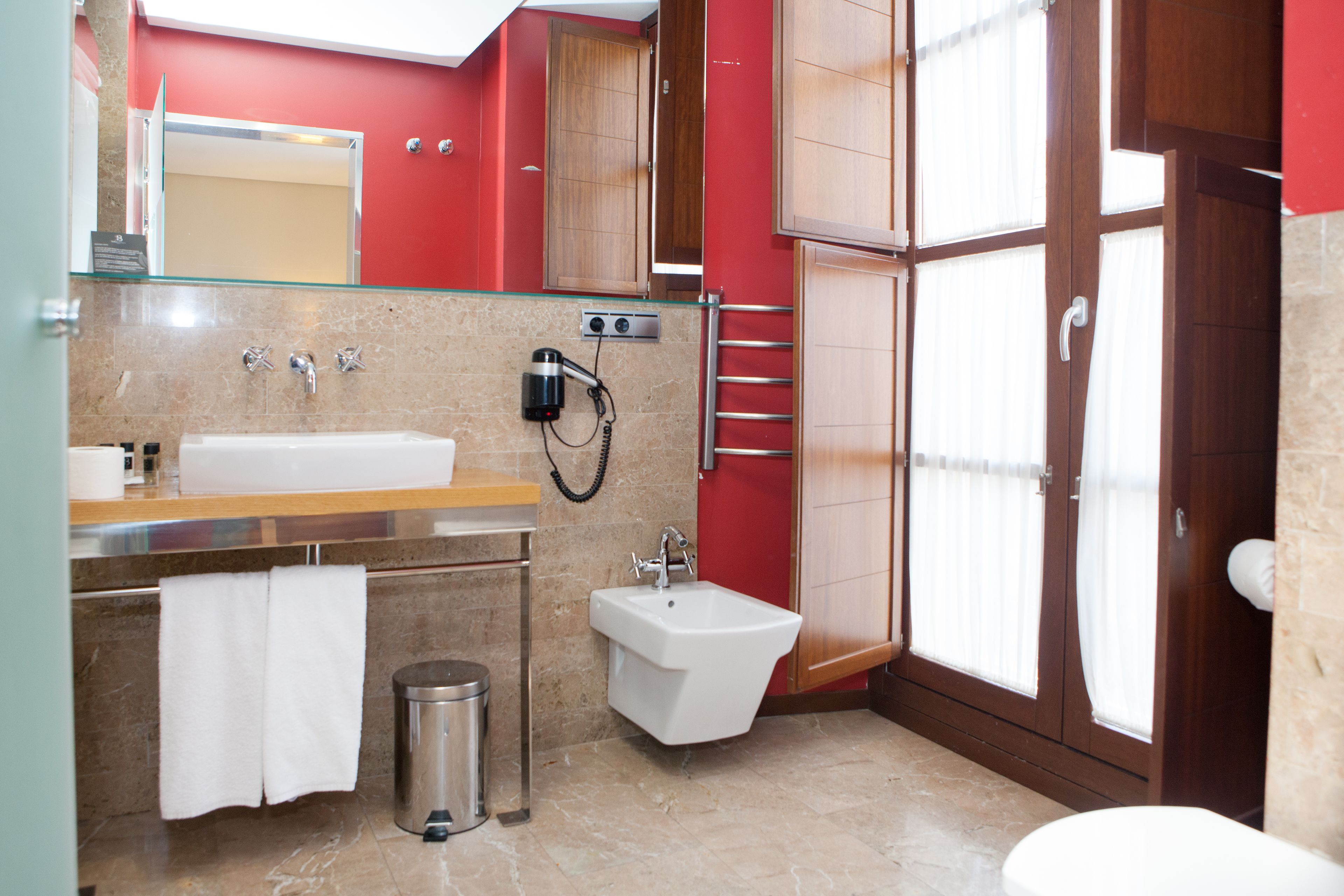 A modern bathroom with a glass partition, a sink, a bidet, a toilet, and a shower area.