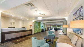 A hotel lobby with a reception desk, seating area, and a dining section in the background. - Sleep Inn & Suites Dover University Area (Dover)