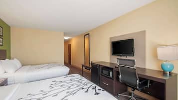 Habitación de hotel con dos camas, un escritorio con computadora, un televisor y una lámpara.
