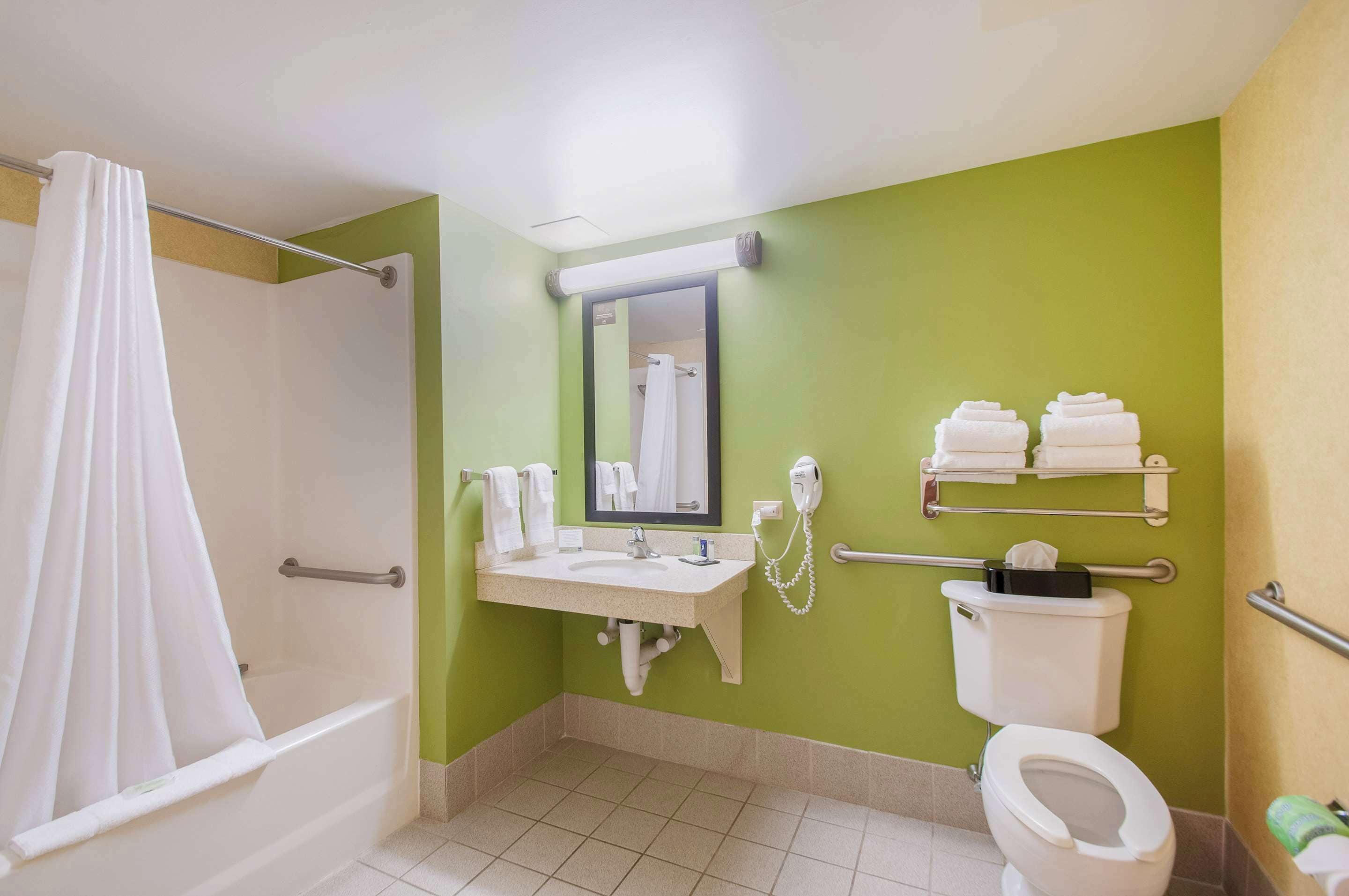 A bathroom with a shower, sink, toilet, and towel rack.