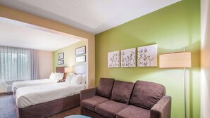 A hotel room with two beds, a sofa, a lamp, and wall art. - Sleep Inn & Suites Dover University Area (Dover)