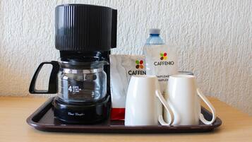 A coffee maker, two white mugs, and a Caffè Nero water bottle on a tray.