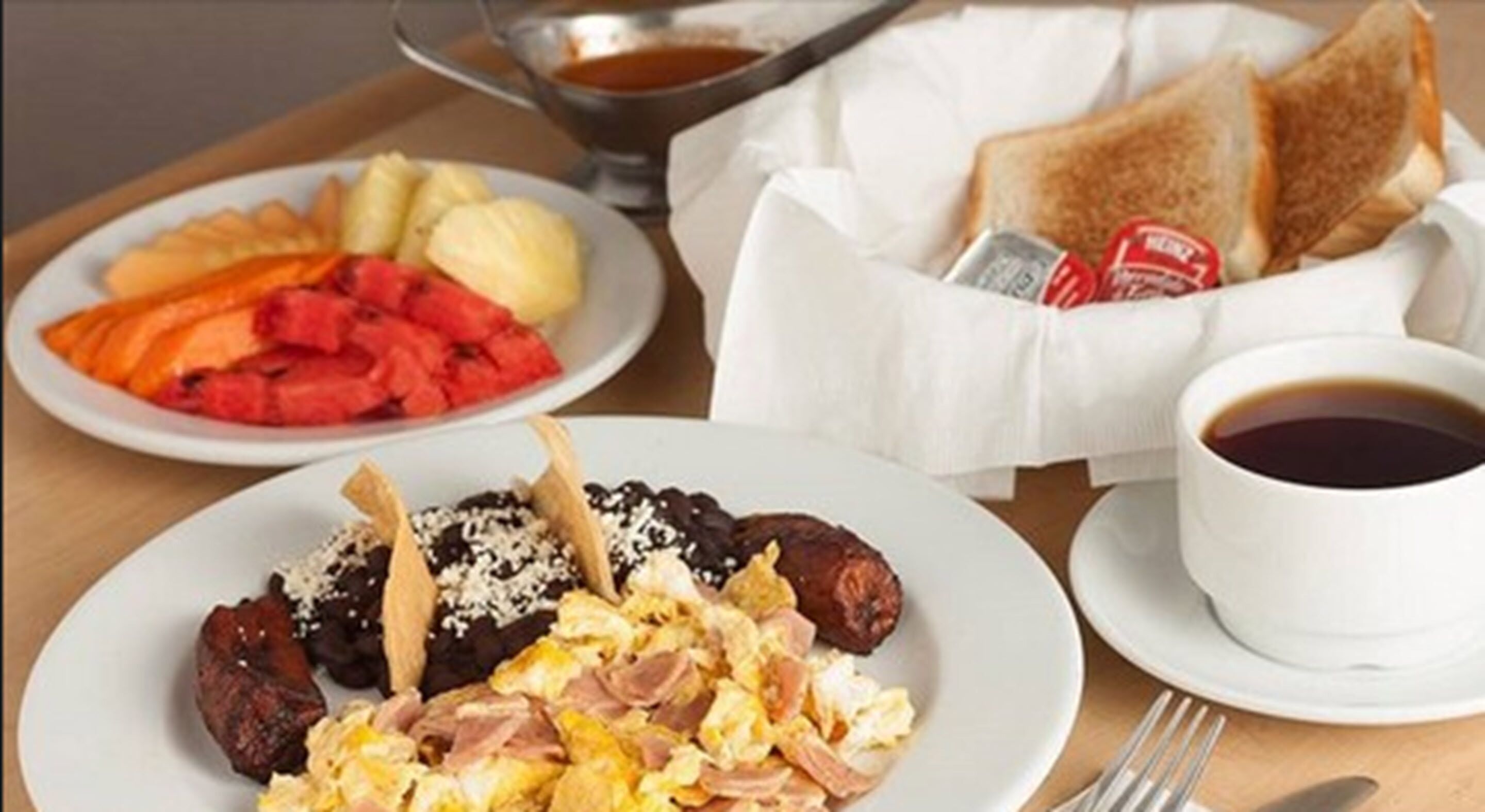 A breakfast setting with plates of food, toast, and a cup of coffee.