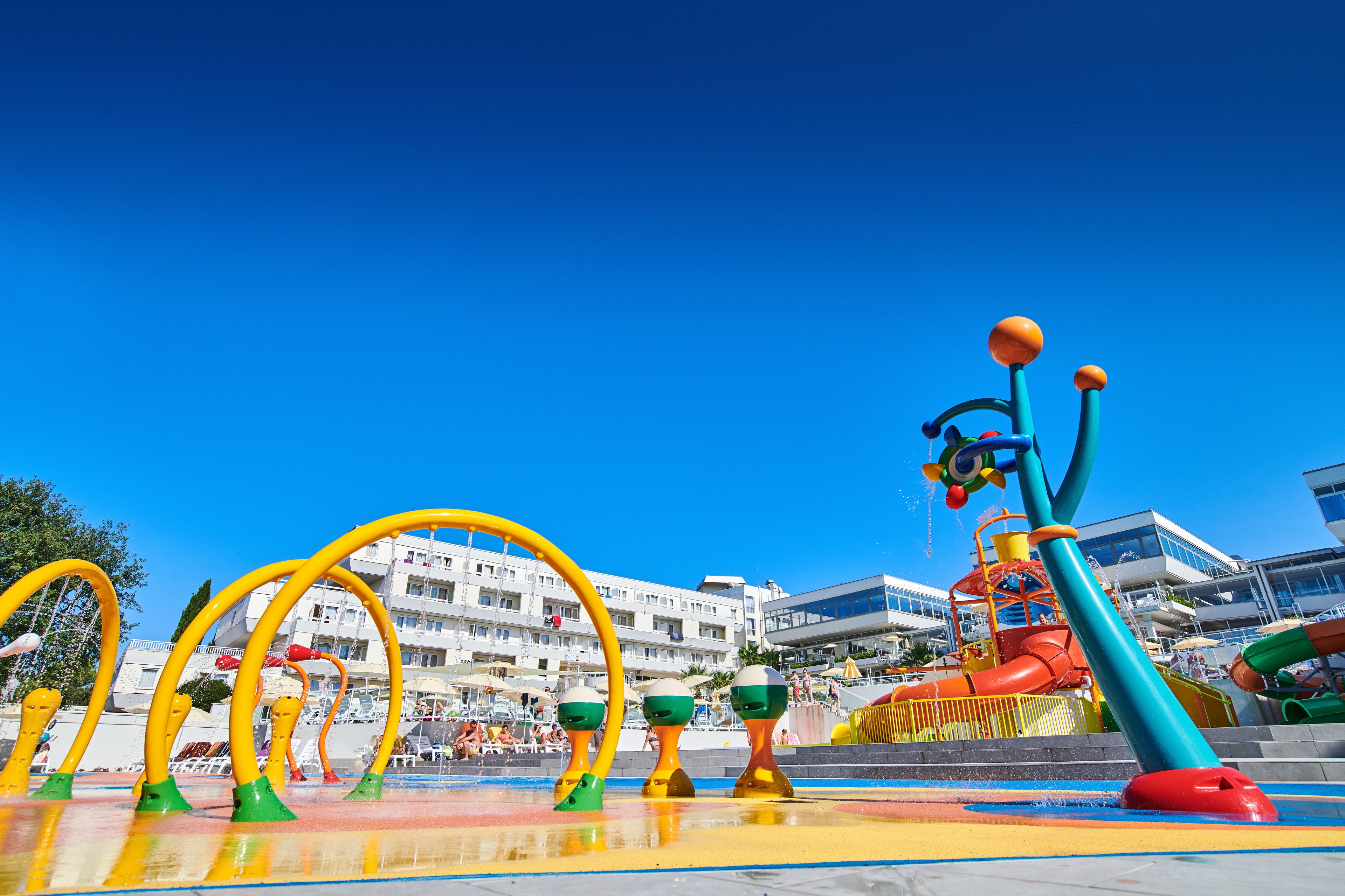 A water park with colorful play structures and a building in the background.