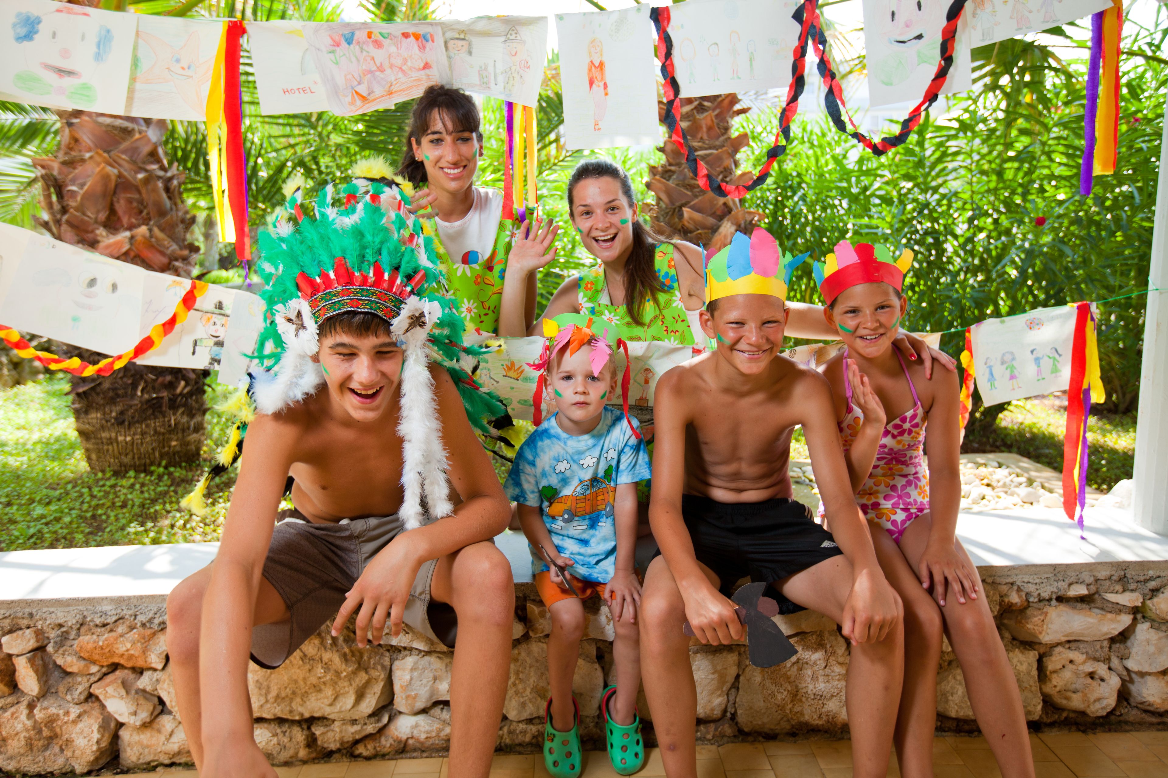 Un gruppo di persone sedute su una panchina di pietra all'aperto, immerse nel verde e decorate con festoni colorati.