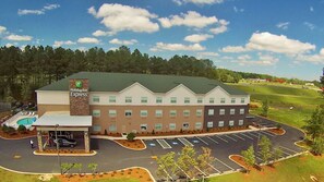 A Holiday Inn Express hotel with a swimming pool, a parking lot, and a golf course in the background. - Holiday Inn Express Defuniak Springs by IHG (De Funiak Springs)