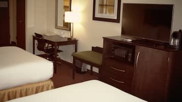 Habitación de hotel con dos camas, un escritorio con una silla, una televisión y un minibar.