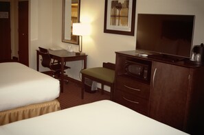 Ein Hotelzimmer mit zwei Betten, einem Schreibtisch mit Stuhl, einem Fernseher und einer Minibar.