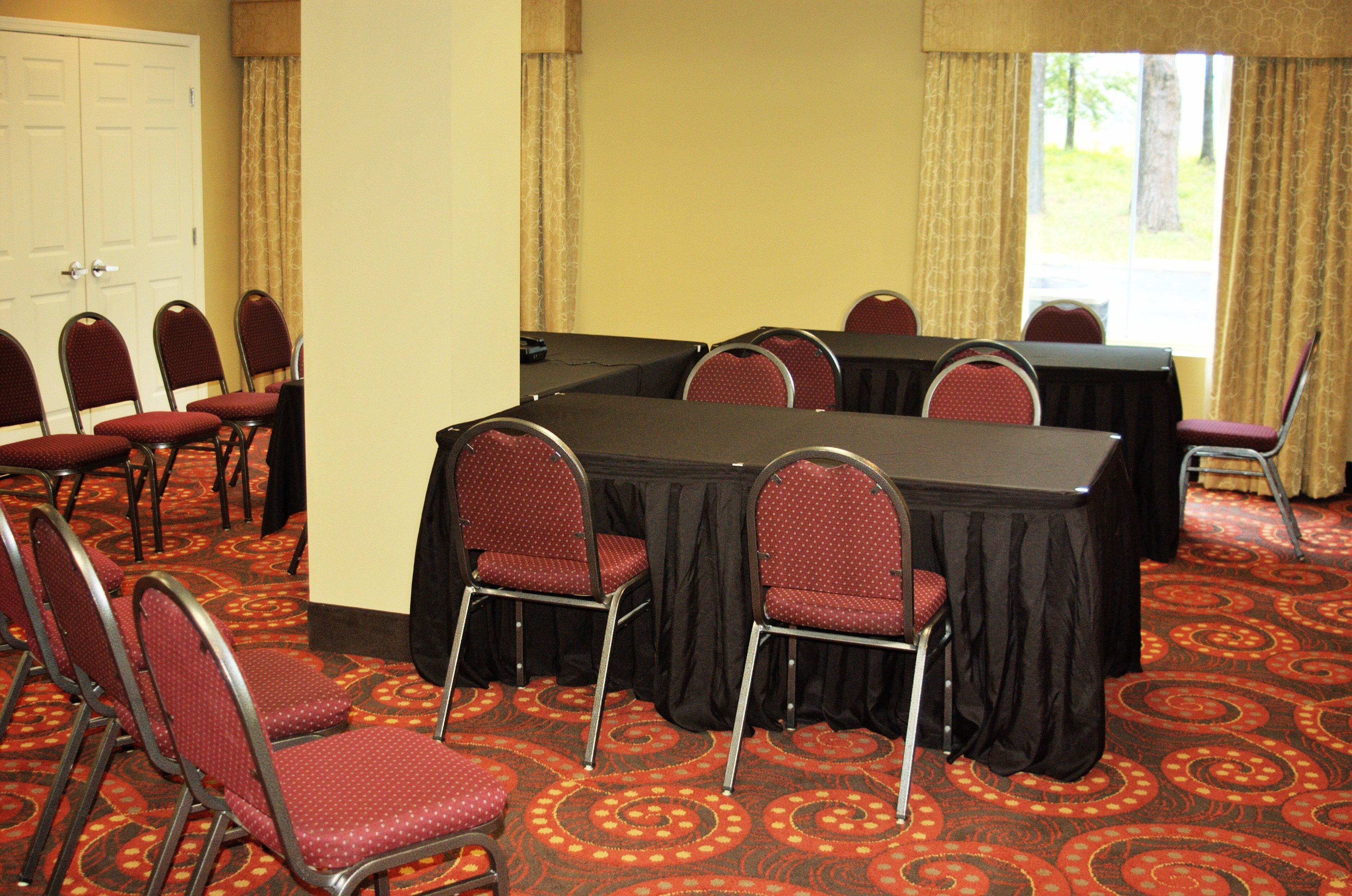 Una sala conferenze con un tavolo grande, diverse sedie e pavimento rivestito di moquette.
