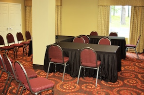A conference room with a large table, multiple chairs, and a carpeted floor.