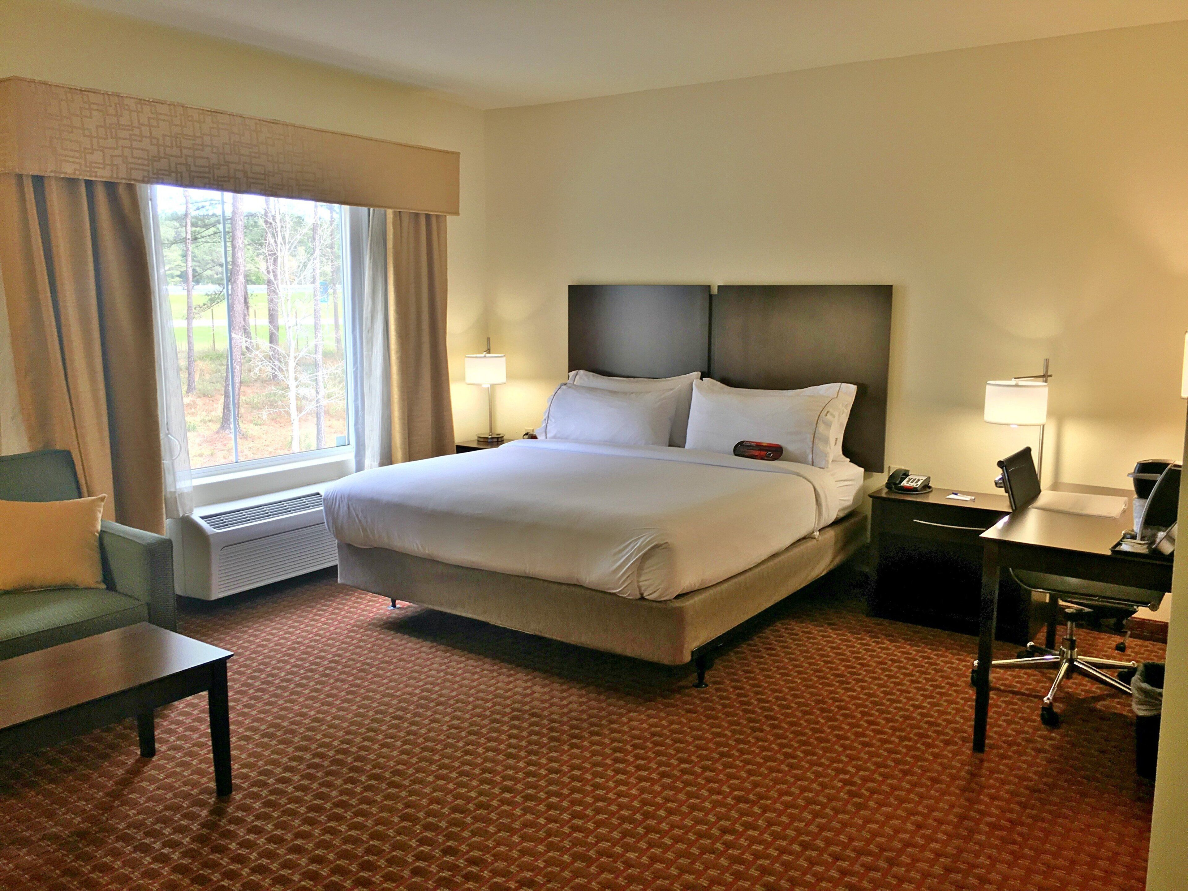 A hotel room with a large bed, bedside tables, a desk, and a chair.
