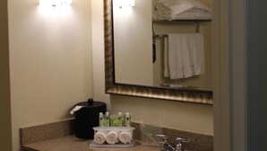 Une salle de bain d’hôtel équipée d’un lavabo, d’un miroir, d’un porte-serviettes et d’articles de toilette.