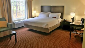 Une chambre d’hôtel avec un grand lit, deux tables de chevet avec des lampes, un bureau, une chaise et une fenêtre avec des rideaux.