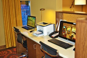 Escritorio de hotel con una computadora portátil, computadora de escritorio, impresora y teléfono.
