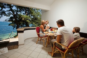 A family dining at a table with a view of the sea.
