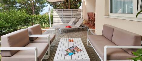 Une terrasse avec une table blanche, deux canapés beige et une chaise blanche.